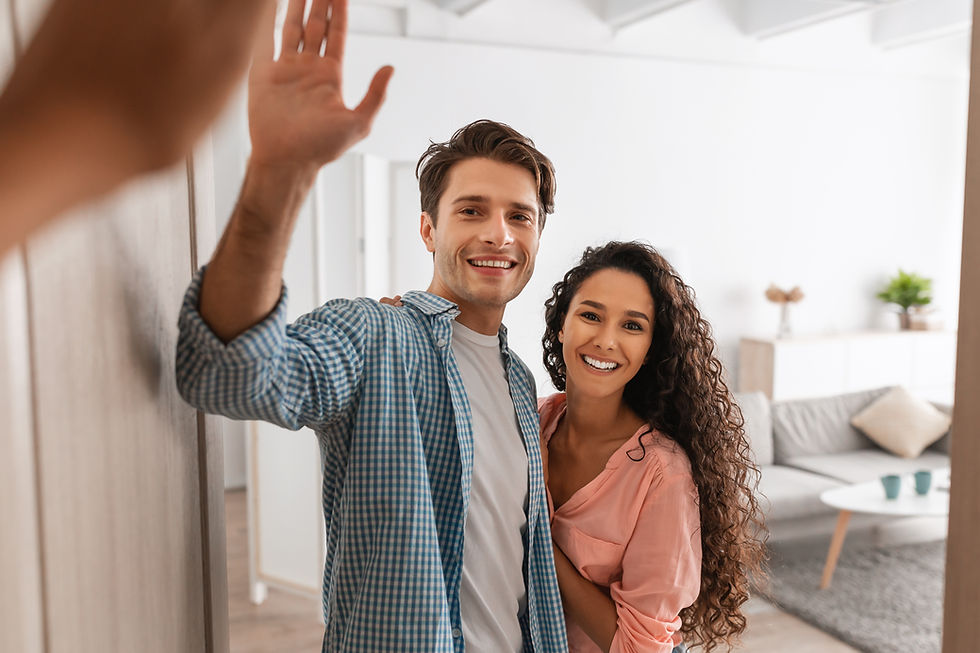 Smiling man and woman embrace. The man is waving to someone off camera
