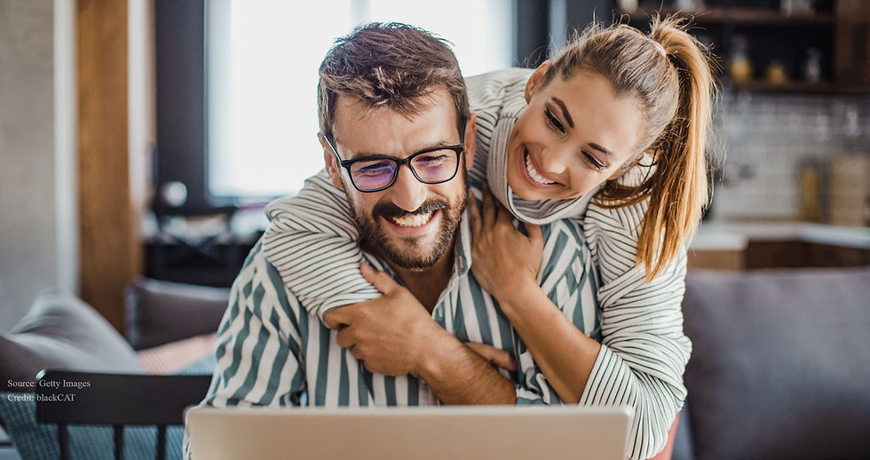 Smiling married couple sitting together and looking at a computer screen. Source: Getty Images. Credit:  blackCAT
