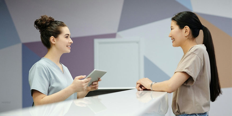 Two women having a conversation at a reception desk (models).