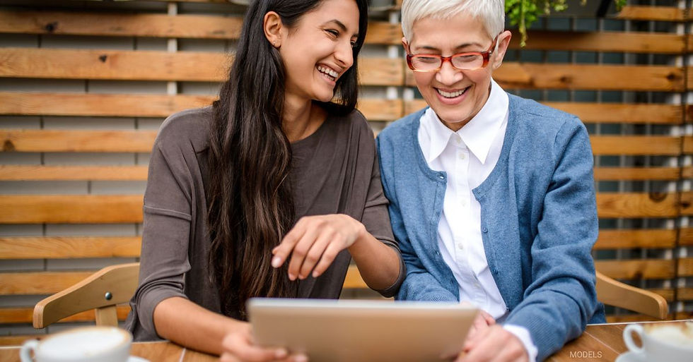 A young woman and an older woman smiling while staring at a tablet