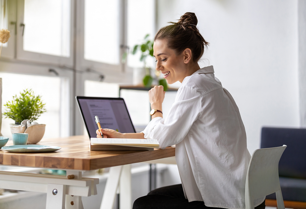 Woman taking notes in front of her computer at her desk